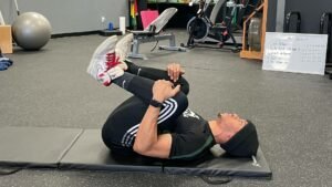 personal trainer showing how to do a Knees to Chest