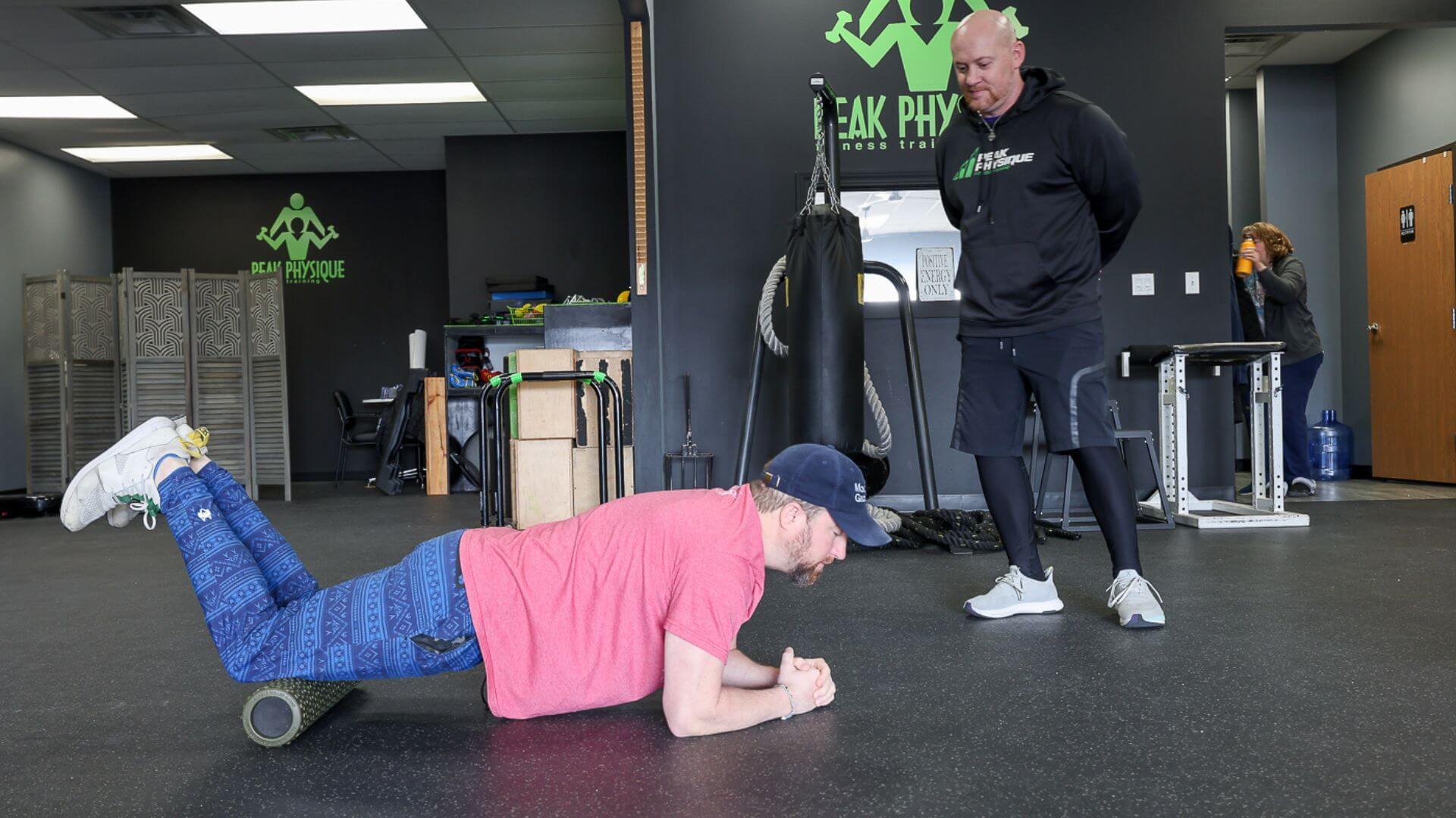 nick, personal trainer at peak physique, watching a client use a foam roller