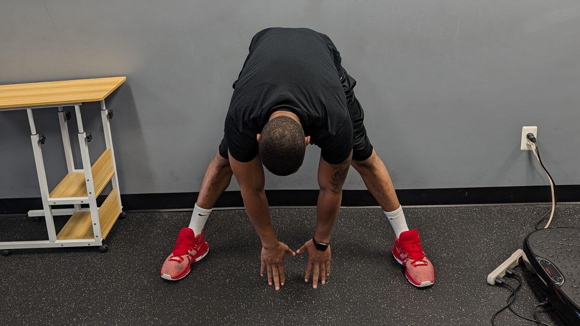 personal trainer showing how to do a Standing Separate Leg Stretch