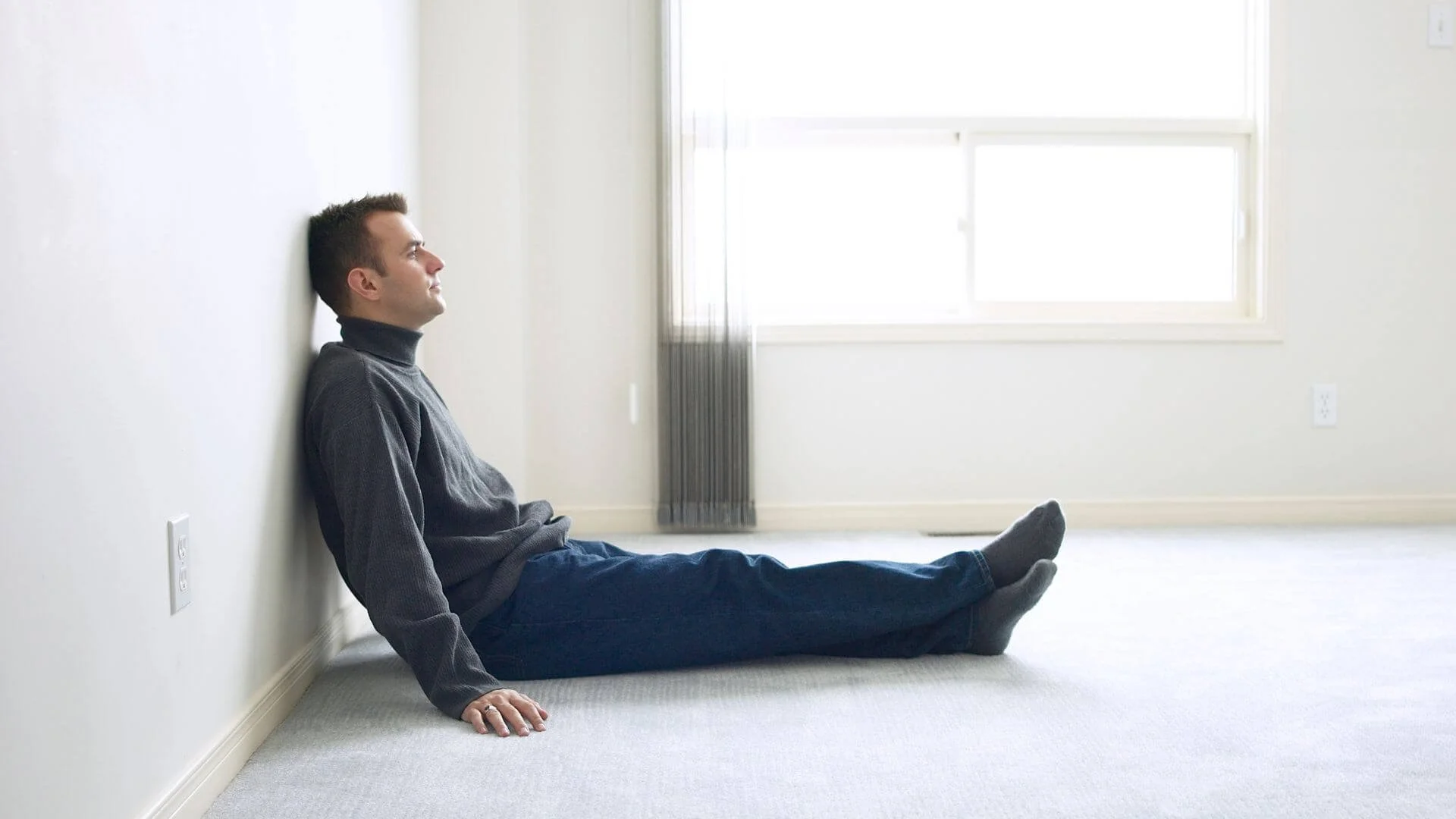 man leaning against a wall feeling no motivation to exercise