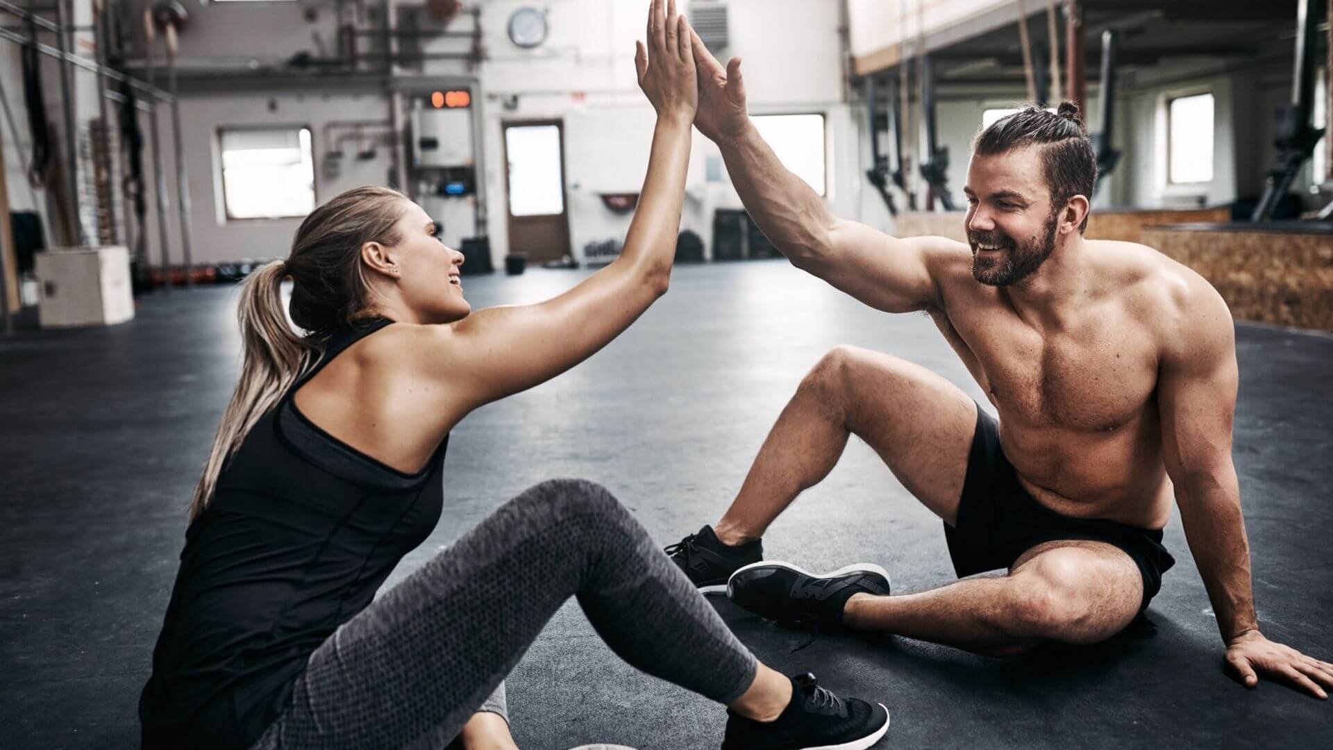 two friends high fiving in the gym