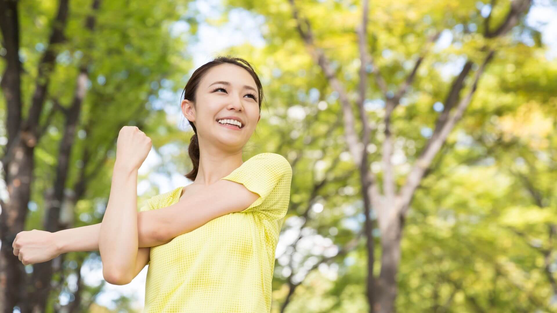 woman smiling outside while stretching on a beatiful day