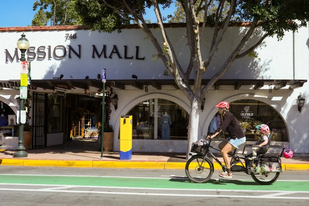 Person riding cargo bike with child on the back on a downtown street in San Luis Obispo California