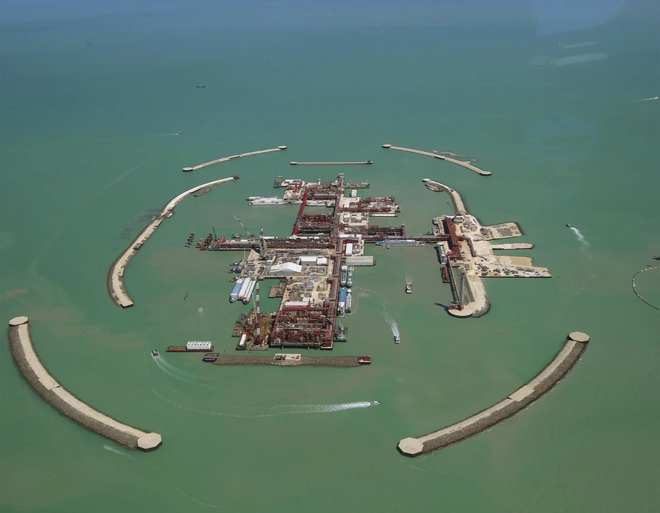 Shell Kazakhstan B.V Aerial view of a large industrial port surrounded by breakwaters in the ocean.