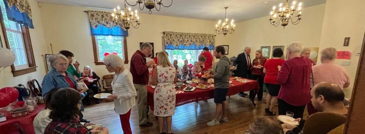 People gathered around a table with food in a decorated dining room celebrating a holiday or special occasion.