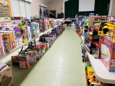Toy aisle in a store with shelves filled with colorful toys and games on both sides, a green curtain and whiteboard at the back.