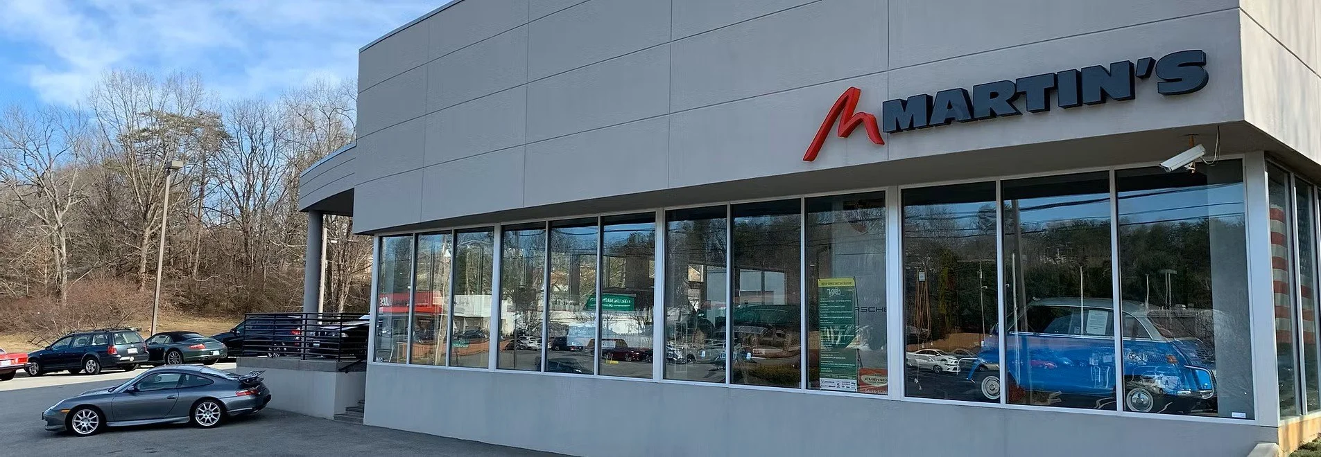Exterior view of Martin's store with large glass windows and a parking lot with several cars. The store has a sign with the name 'Martin's' and a red 'M' logo.