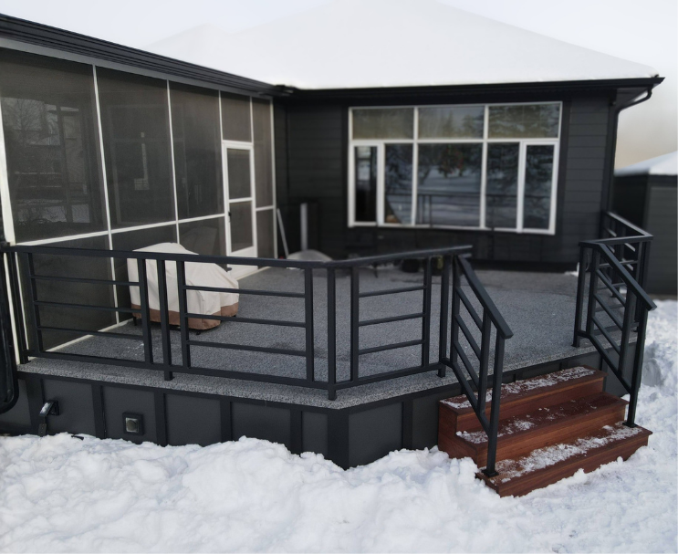 Photo of a house deck with black railing and red wooden stairs, surrounded by snow.