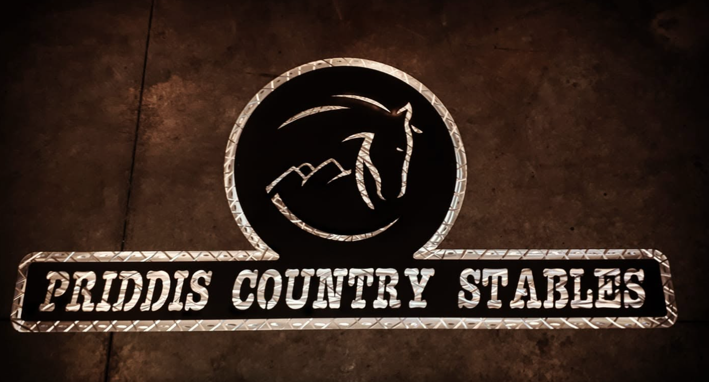 Neon sign with a dragon logo and the words 'Priddis Country Stables' on a dark background.
