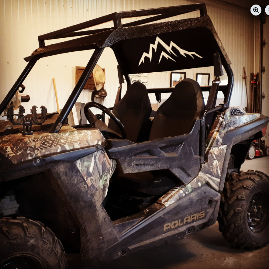 A camouflage Polaris off-road utility vehicle with two black seats inside a garage.