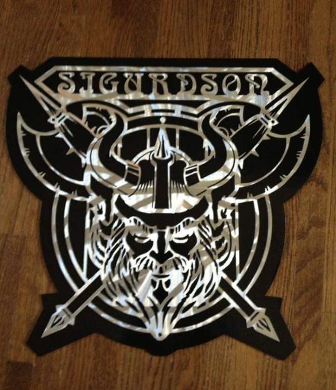 Decorative steel wall art with a Viking warrior theme, featuring a lion's face, swords, and metalwork designs.