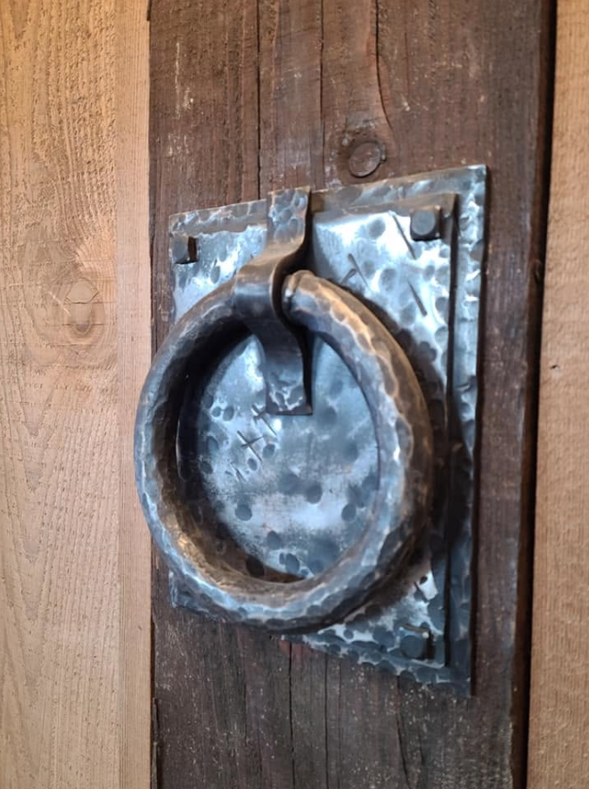 Metal ring door knocker mounted on a wooden door.