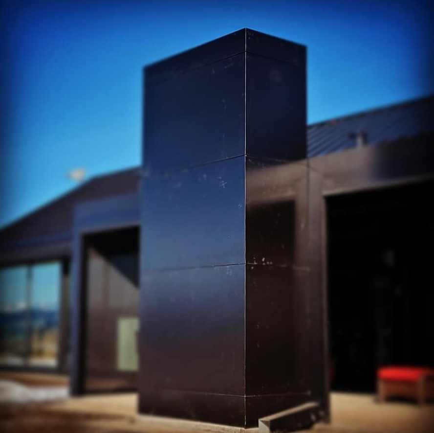 Close-up of a black angular building corner with a clear blue sky in the background.