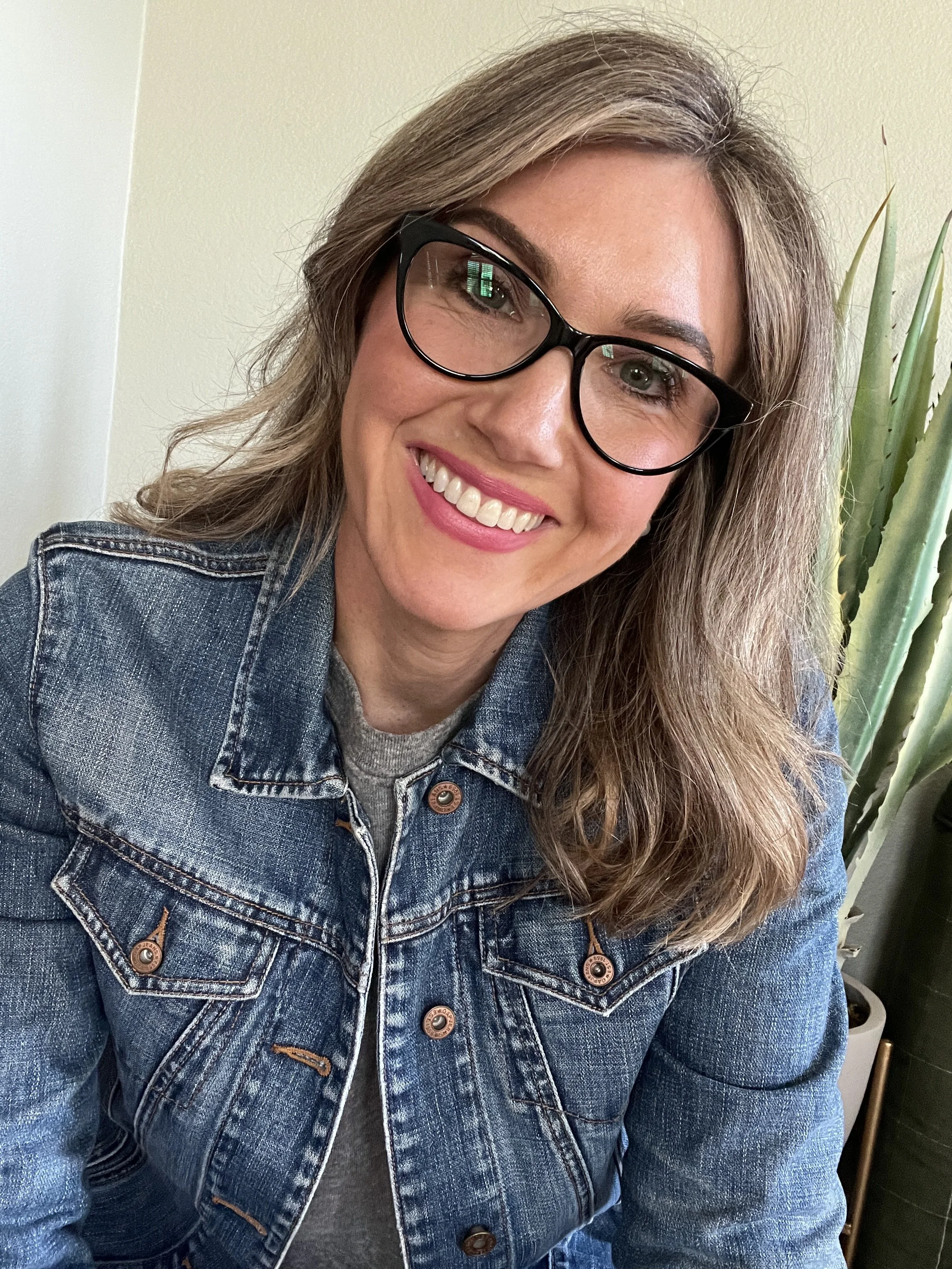 Author and CEO Jamie Moraga smiling at camera with denim jacket and glasses on