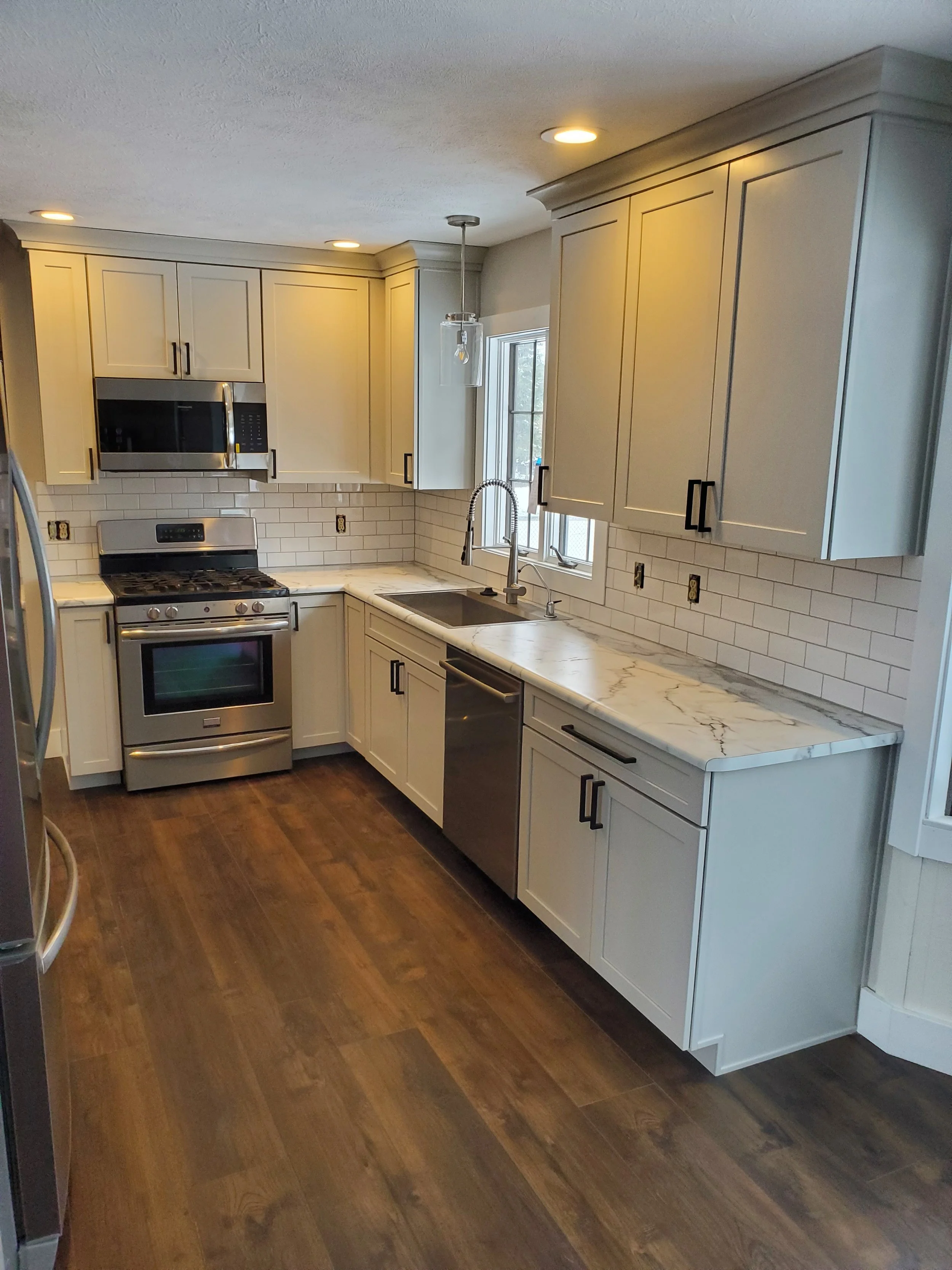Galley kitchen renovation with white cabinets, subway tile backsplash, and under-cabinet lighting for a clean, modern finish.