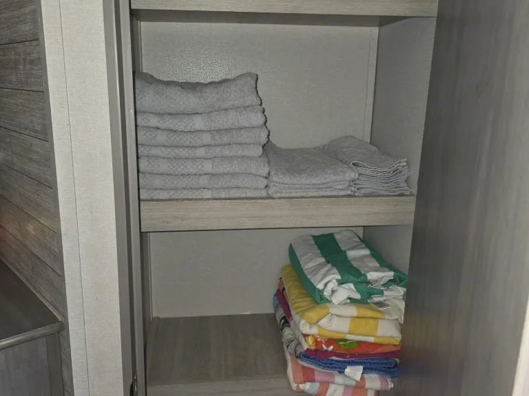 Open closet with neatly folded white and patterned towels on shelves.