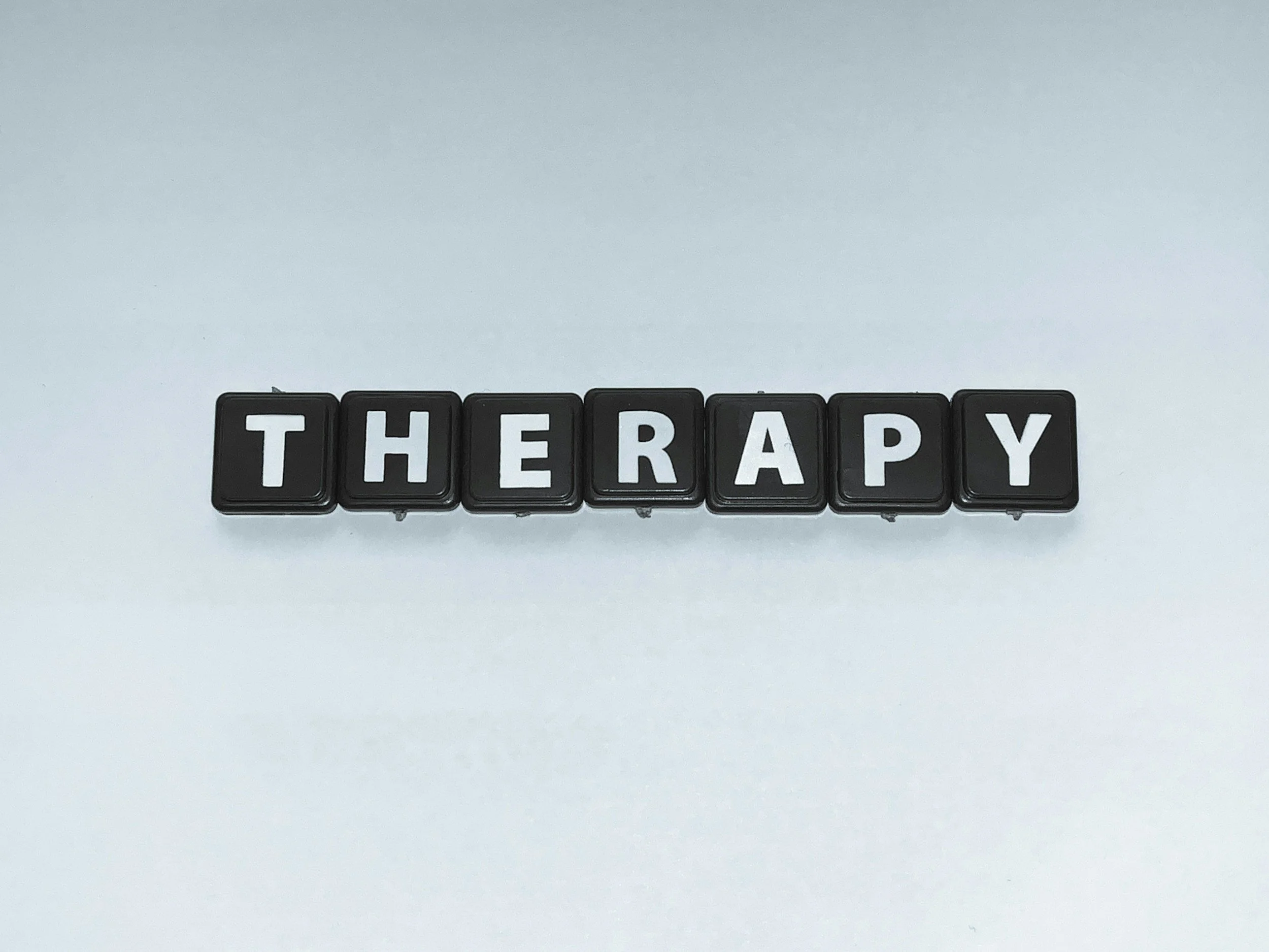 Black letter tiles spelling out "THERAPY" against a white background.
