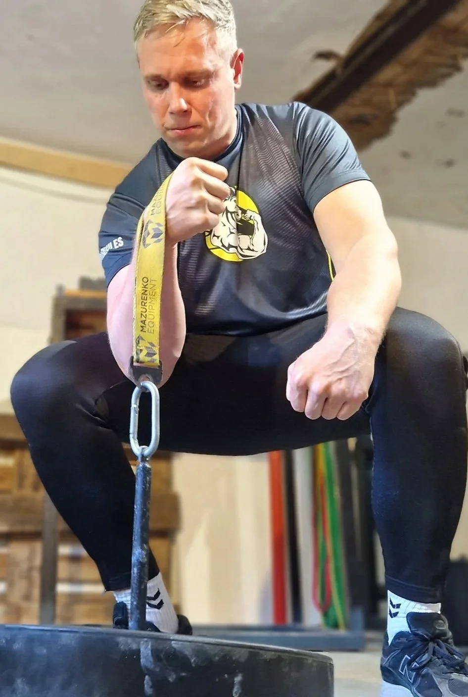Mand, der træner med vægtstang og træningsbælte, i et fitnesscenter.