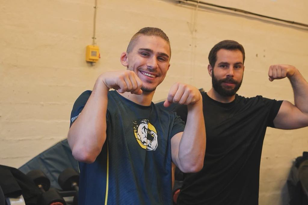 To mænd der viser deres muskler i en fitnesscenter.