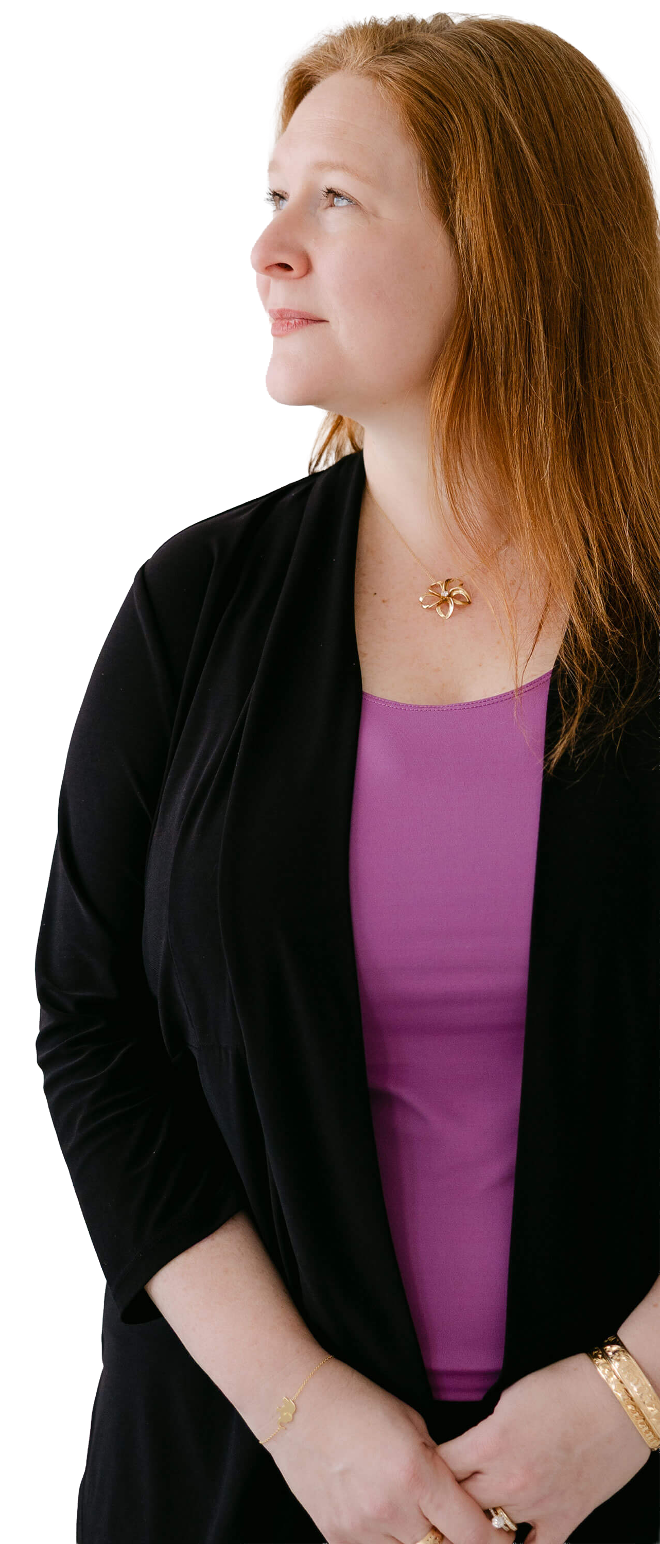 A woman with red hair looking to the side, wearing a black jacket over a purple top, with gold jewelry including a necklace, bracelet, and rings.
