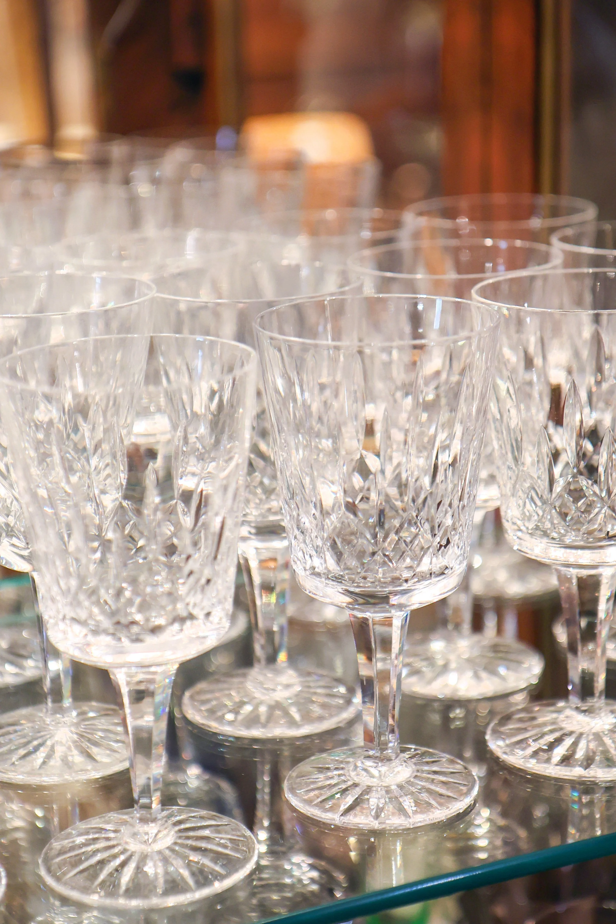 A collection of crystal glasses with intricate cut designs arranged in rows.