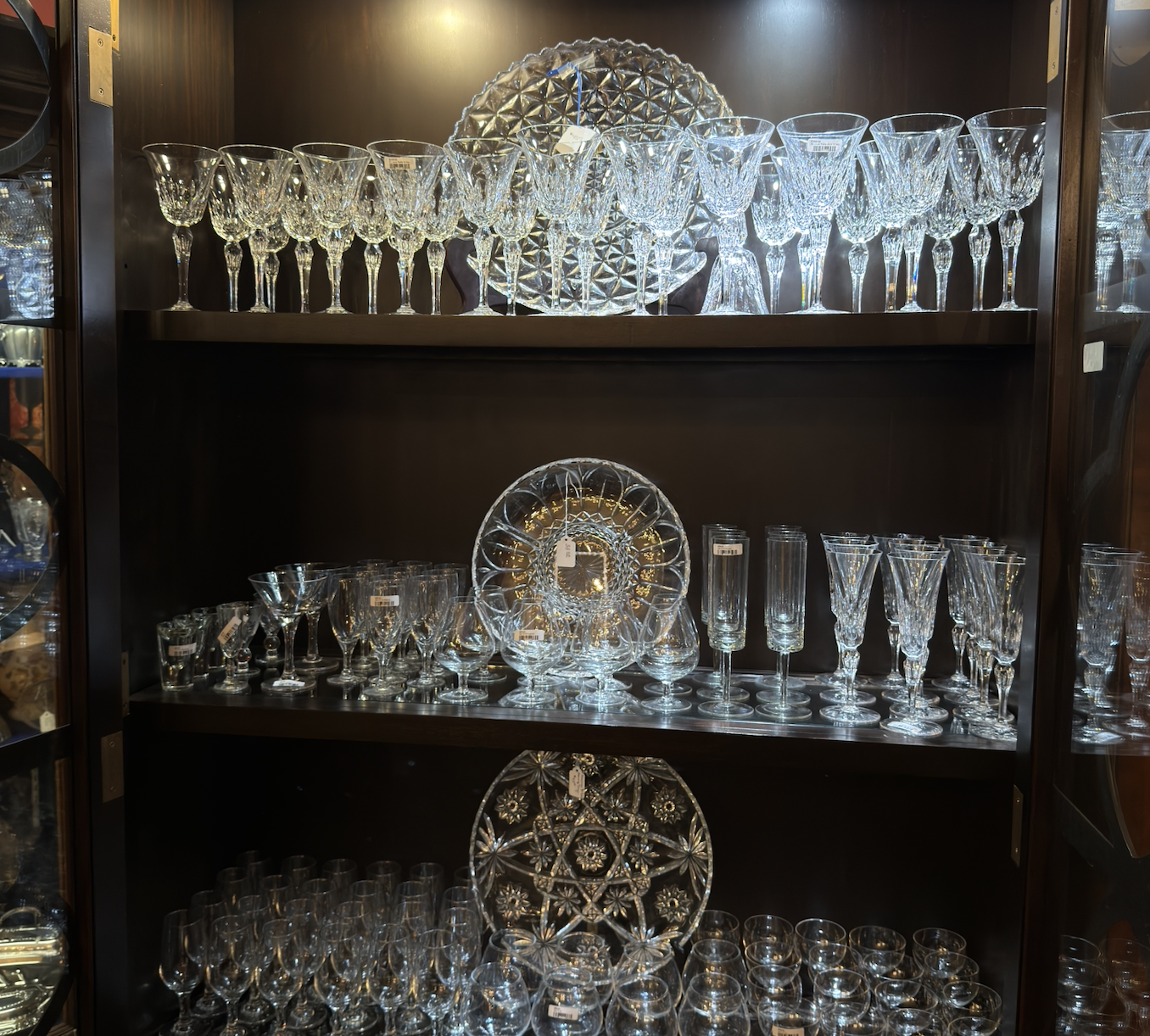 A display cabinet filled with various cut glassware including wine glasses, champagne flutes, and decorative glass plates.