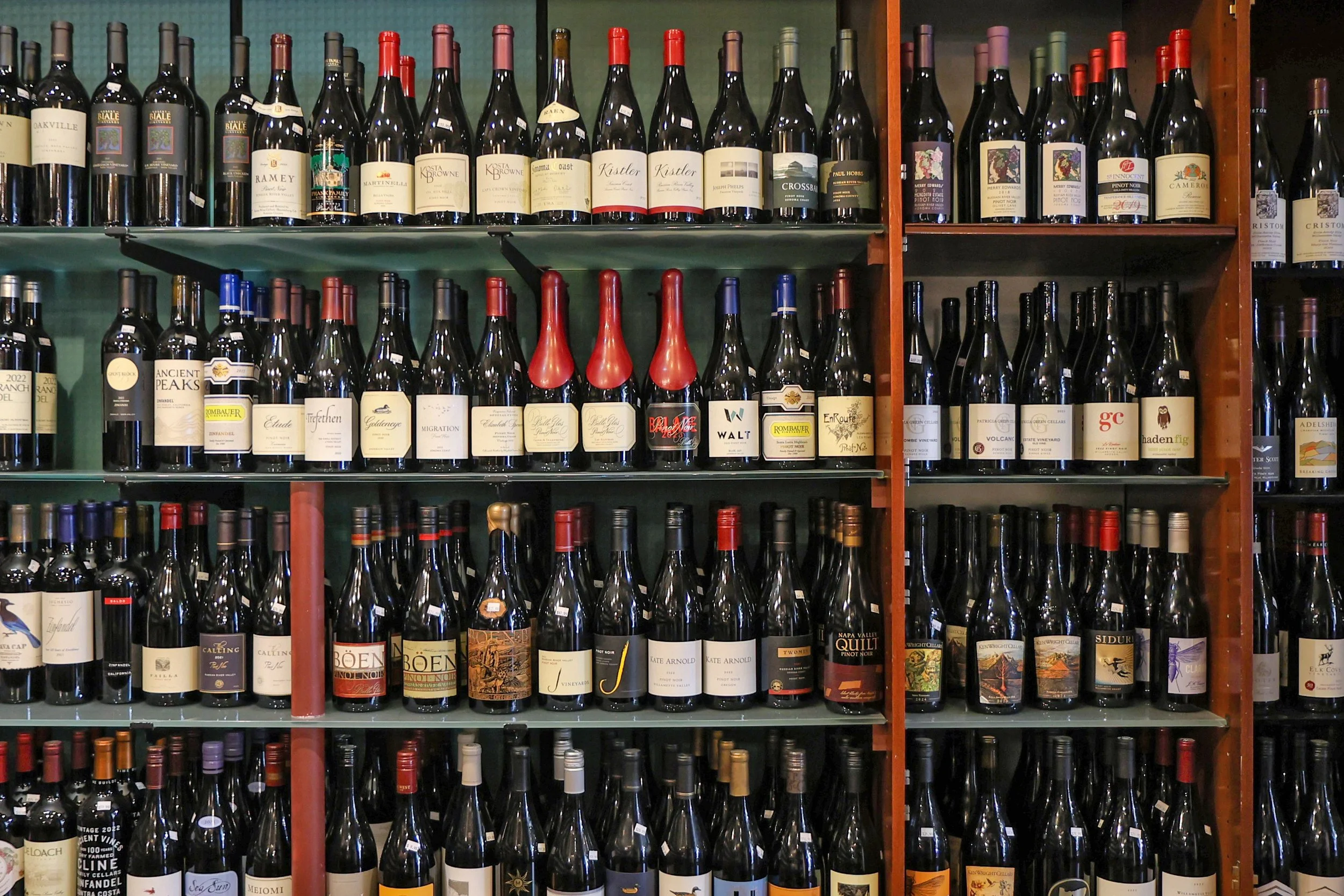 Shelf filled with various bottles of red wine, organized in rows.