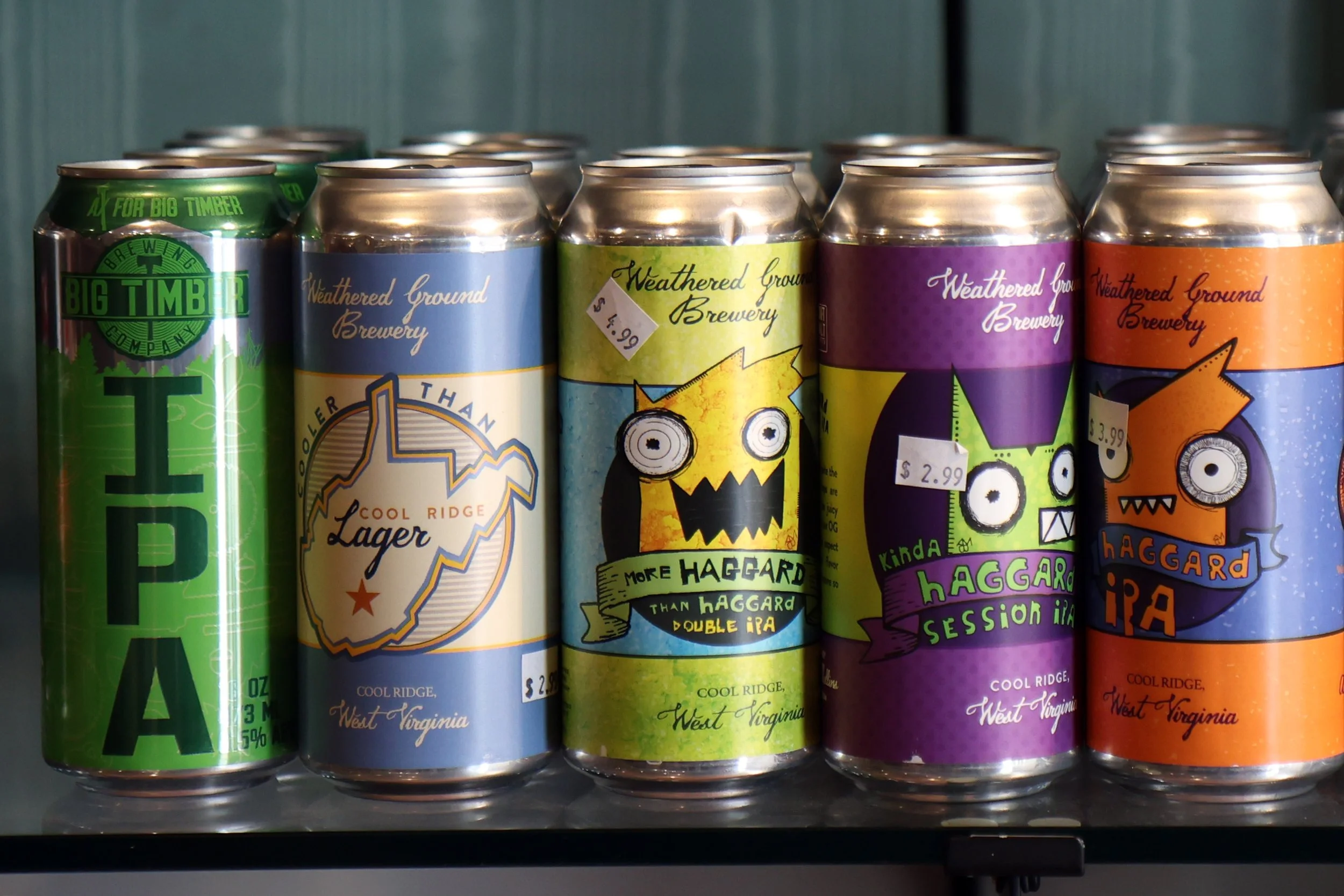 A row of colorful craft beer cans featuring different designs and labels from Weathered Ground Brewery in West Virginia.