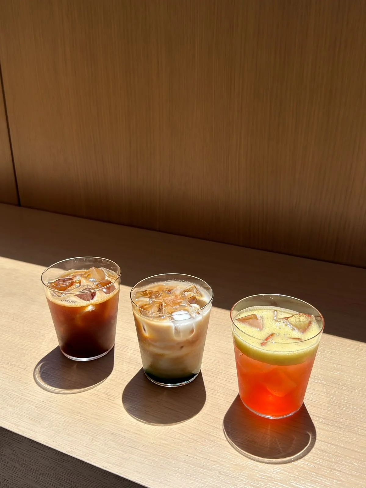 Pouring milk into a plastic cup filled with iced coffee or tea, with a blurry kitchen background.