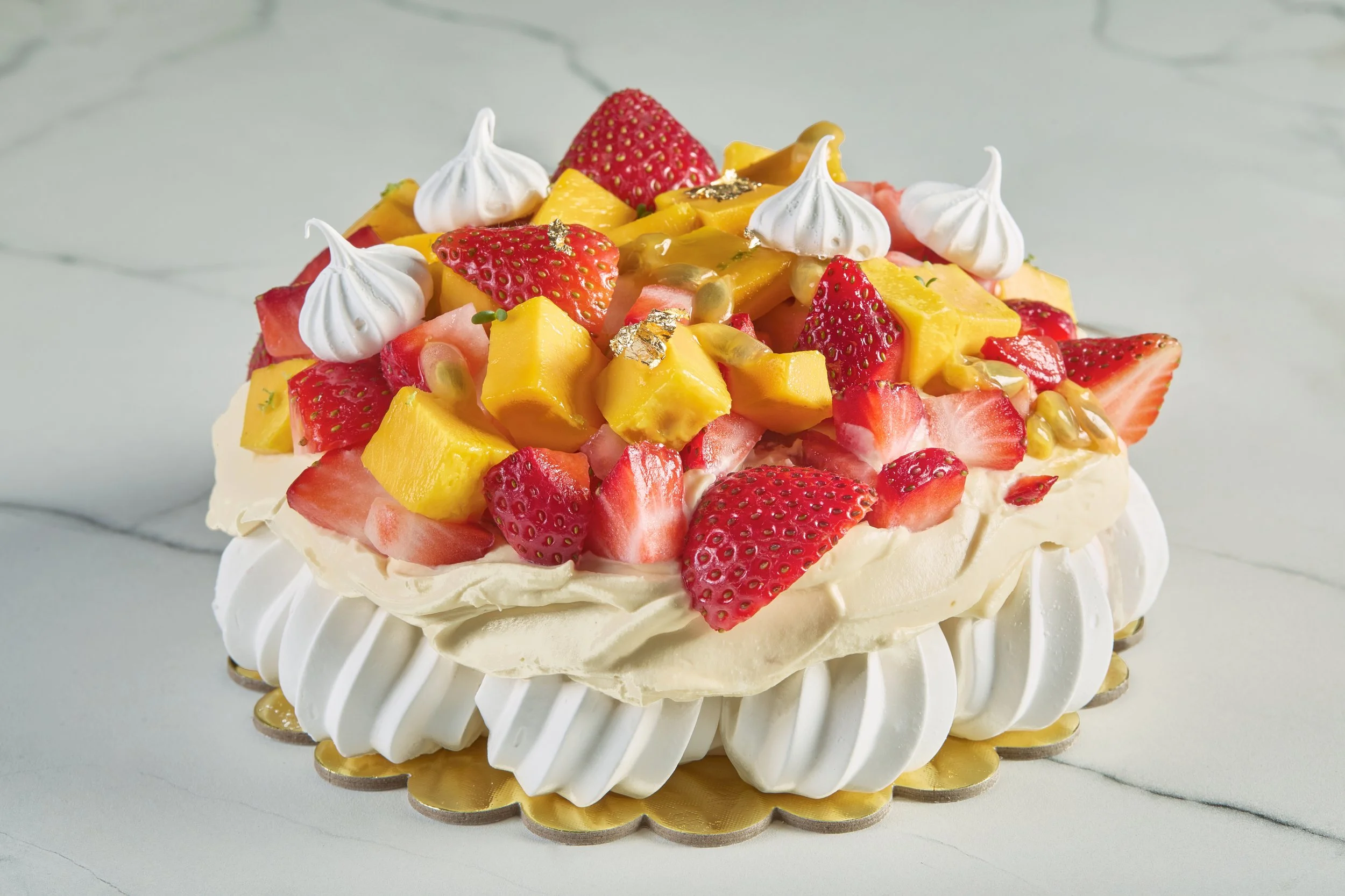 Pastel para cumpleaños tipo pavlova con fruta fresca y decoración elegante.