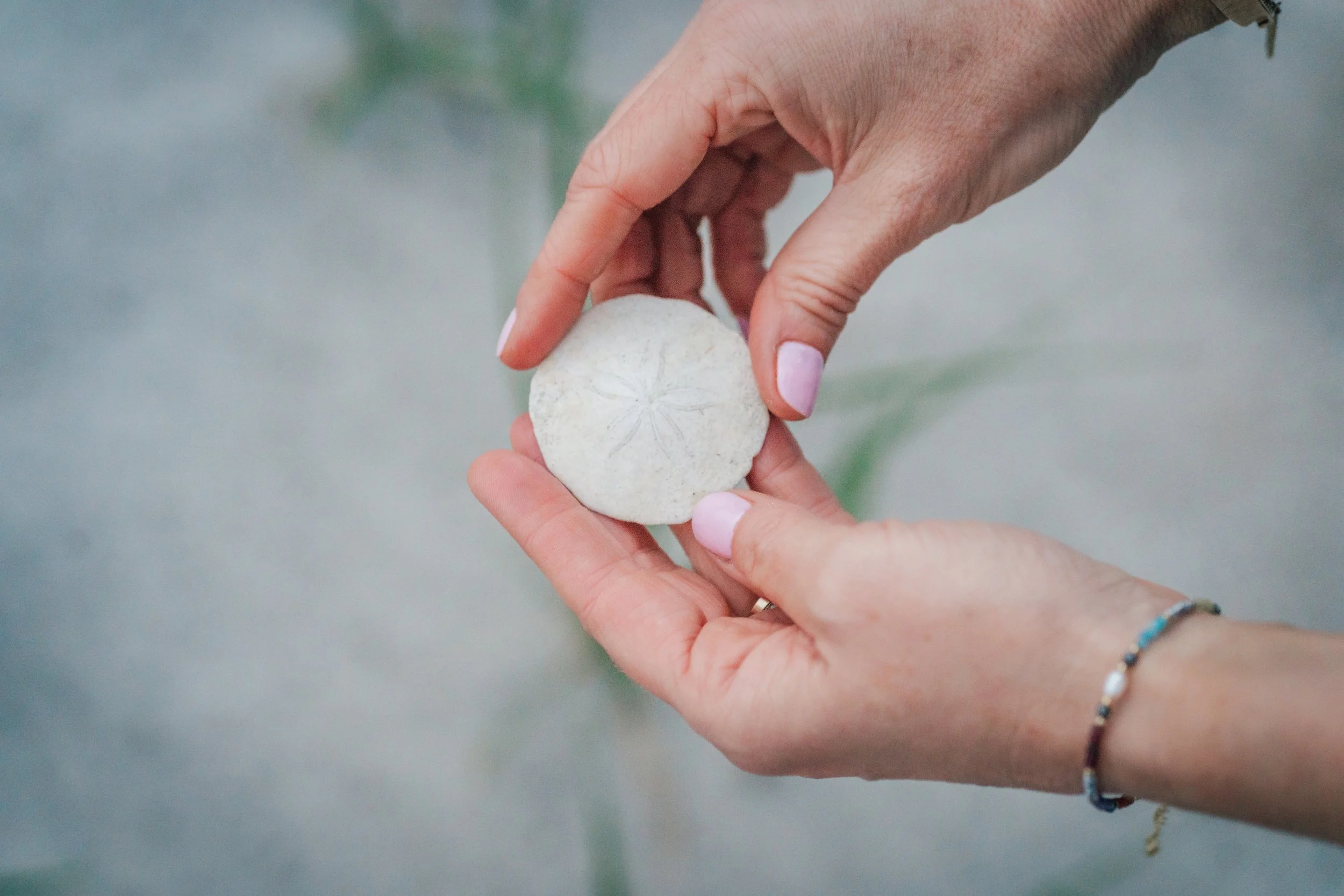Two hands holding a textured, round stone or clay object with a carved star design on it. The background is blurred.