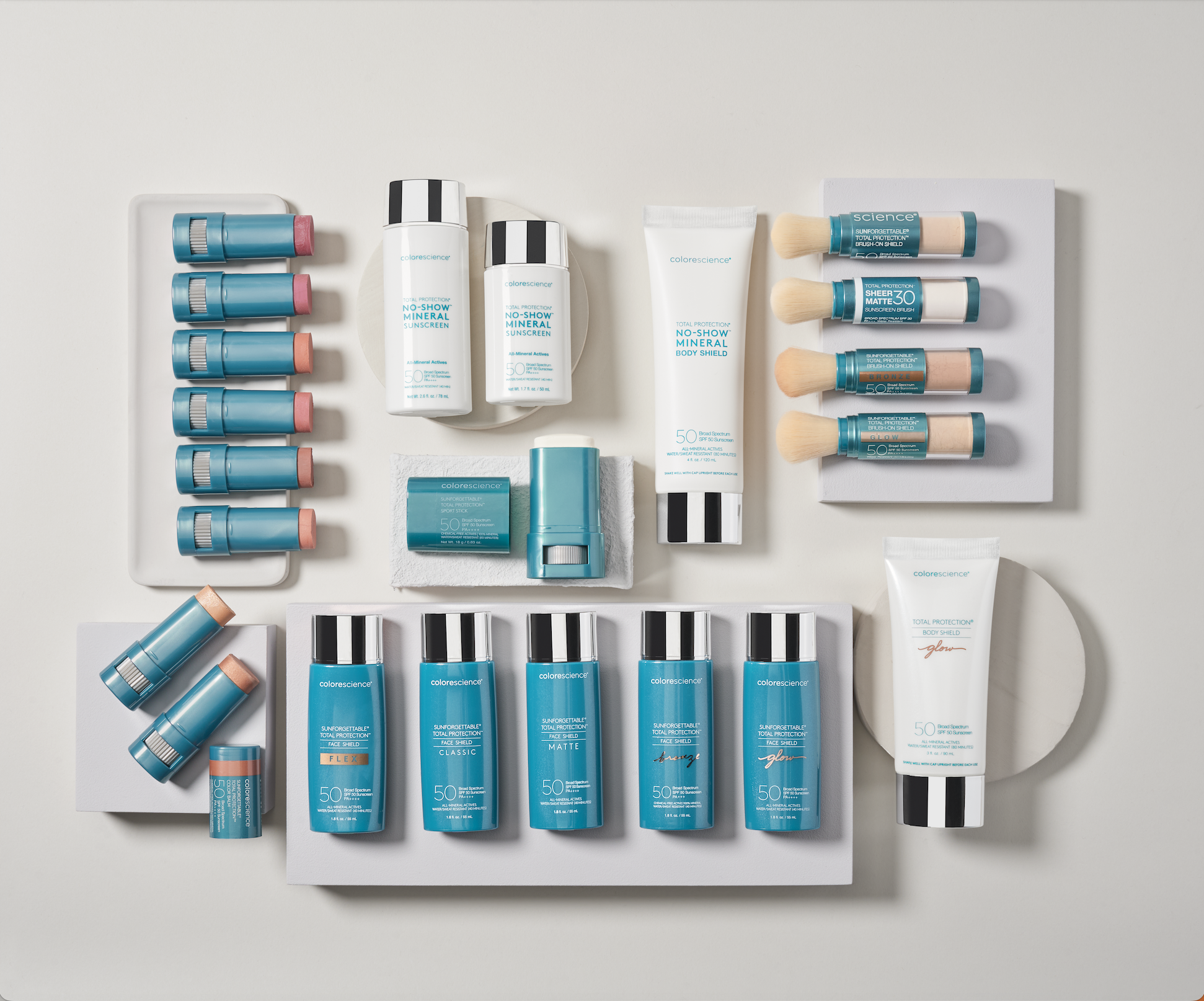 An arrangement of skincare and sunscreen products including tubes and bottles in teal, white, and black packaging on white backgrounds.