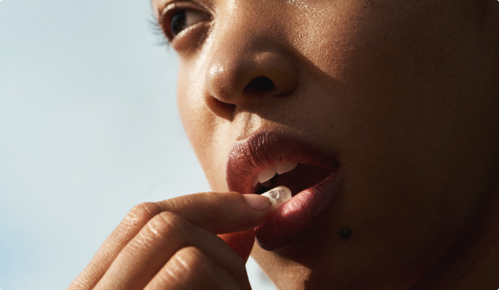 Close-up of a woman taking a pill with her fingers.