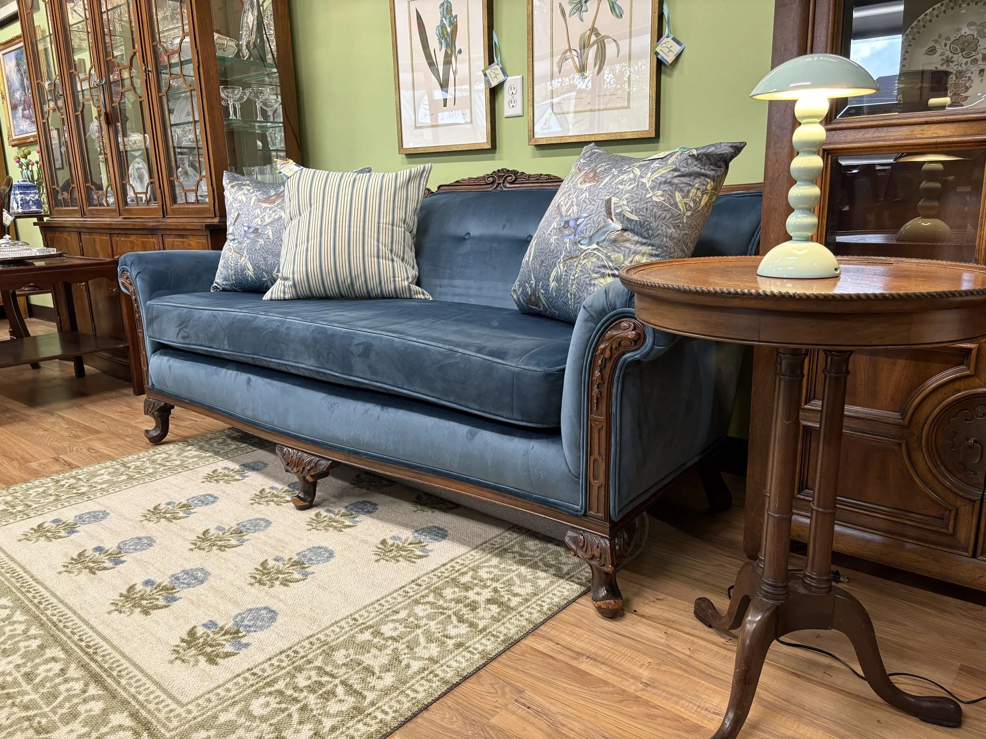 Close-up of an antique Victorian sofa's carved wood arm and turned leg, reupholstered in blue velvet, Evelyn's Emporium Saint Paul.