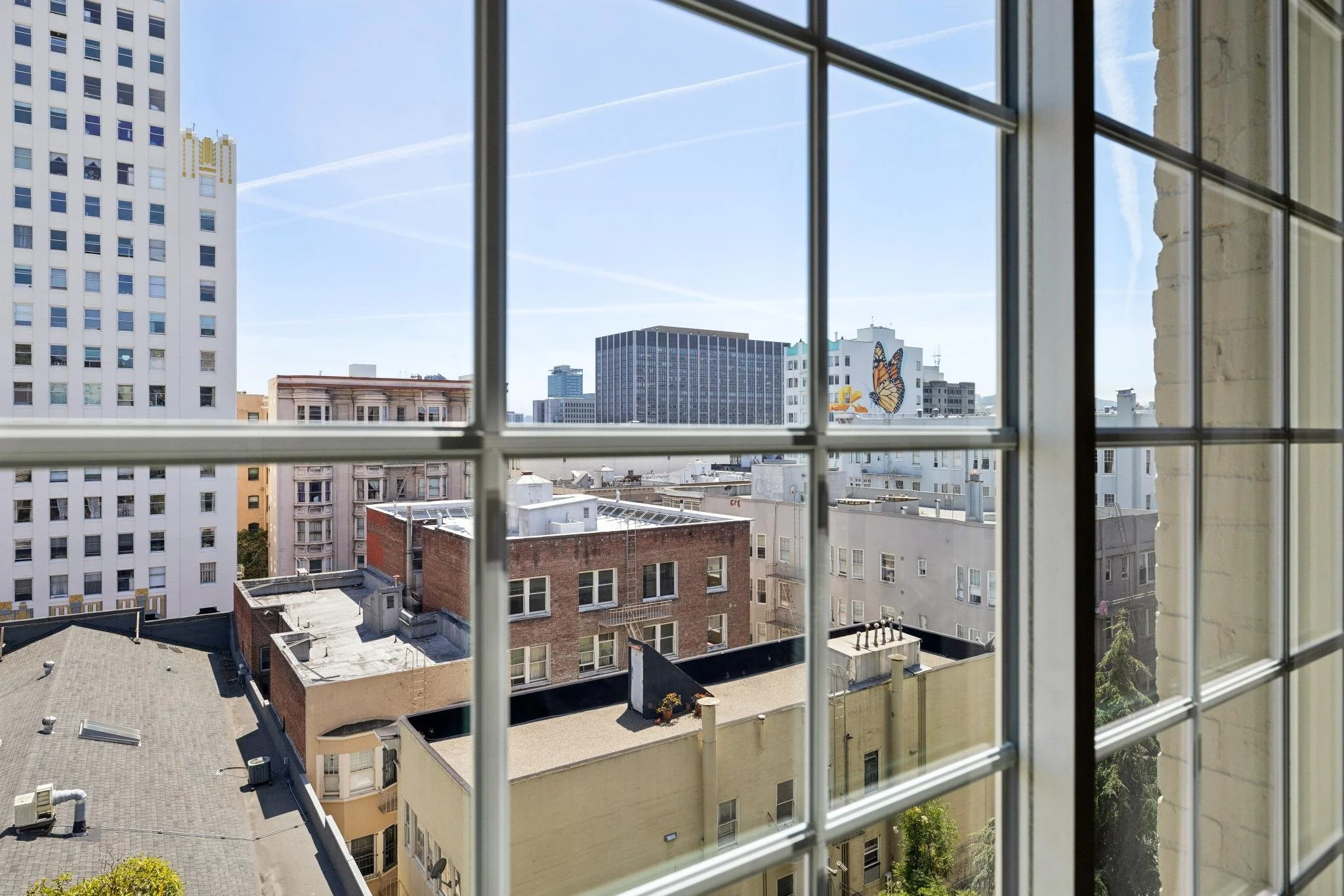 View of city buildings through window with metal grid in an urban setting