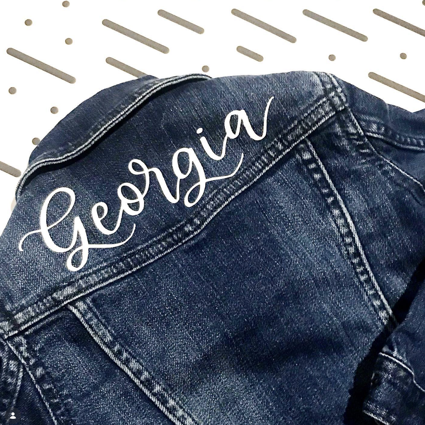 A pair of blue denim jeans with the name "Georgia" written in white cursive text on the back pocket.