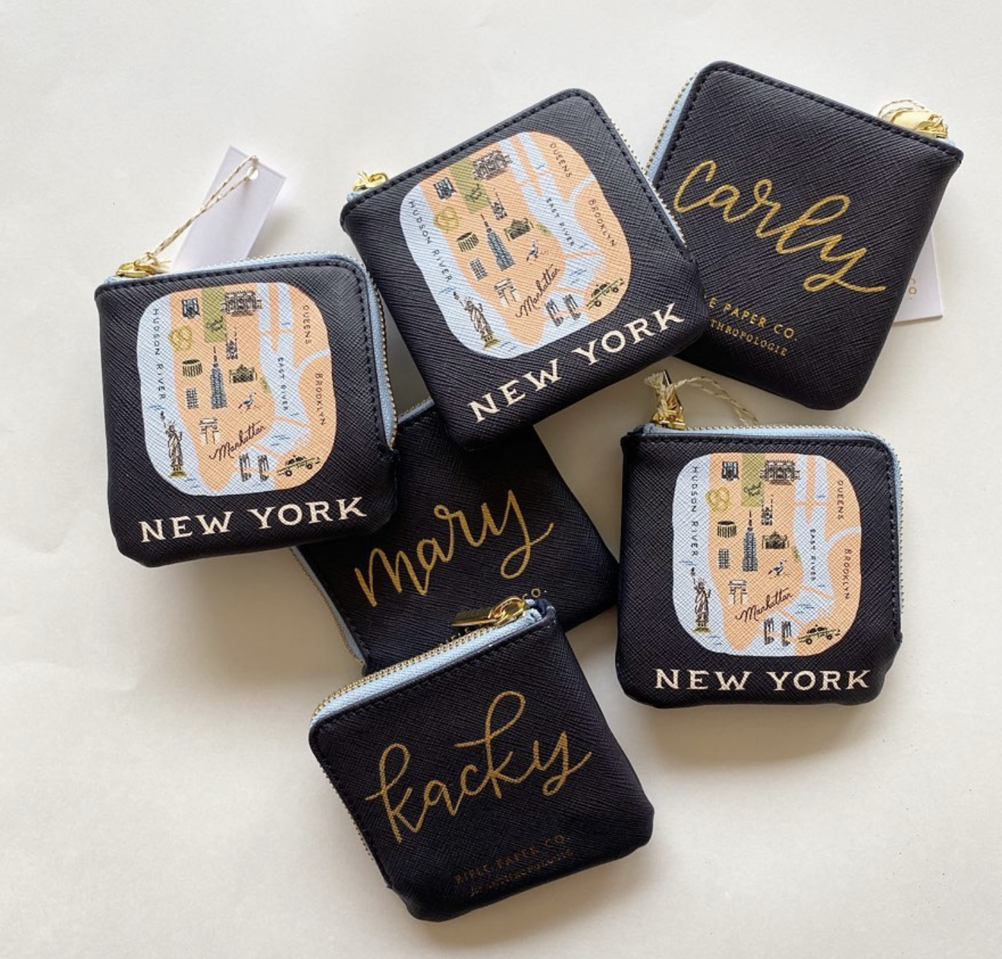 Several small black pouches with gold zipper pulls, some labeled 'new york' and 'marry,' and others labeled 'fucky,' featuring a stylized map of New York City with landmarks and street names.