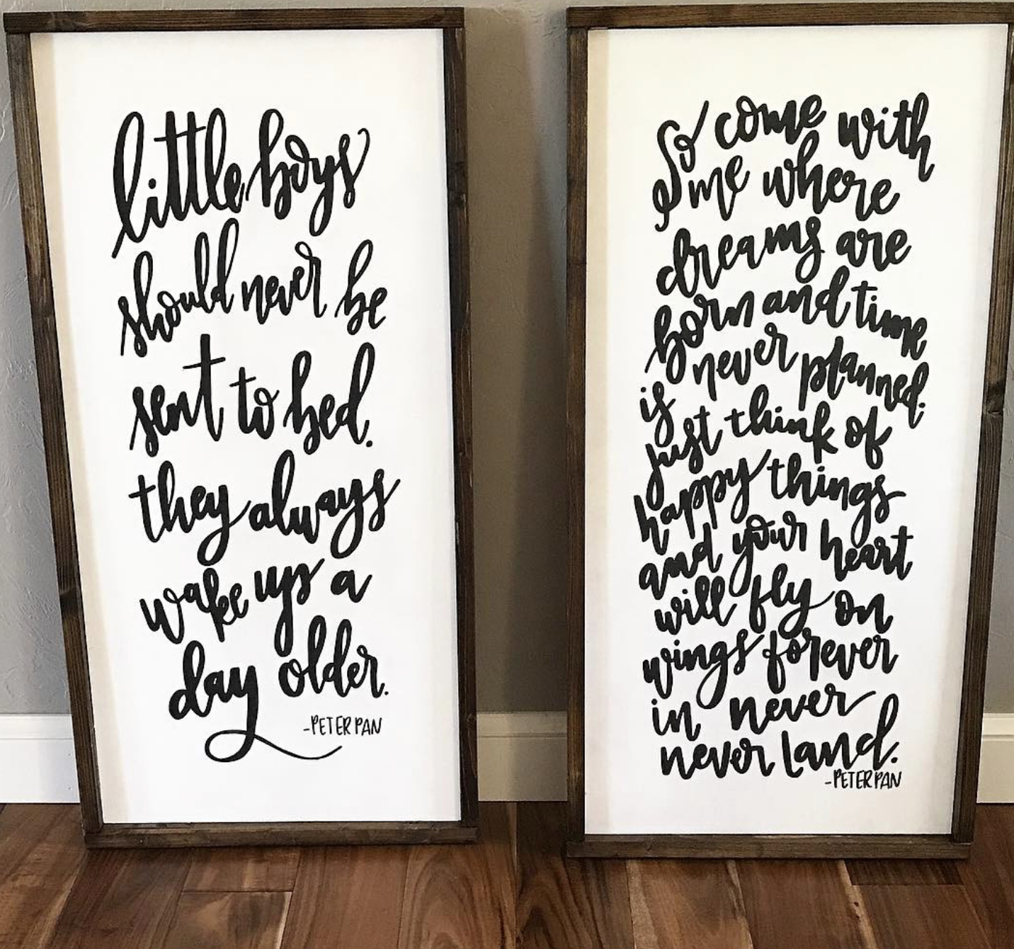 Two wooden-framed signs with black handwritten-style text on a white background. The left sign reads, 'little boys should never be sent to bed. they always wake up a day older. -PETER PAN'. The right sign reads, 'so come with me where dreams are born