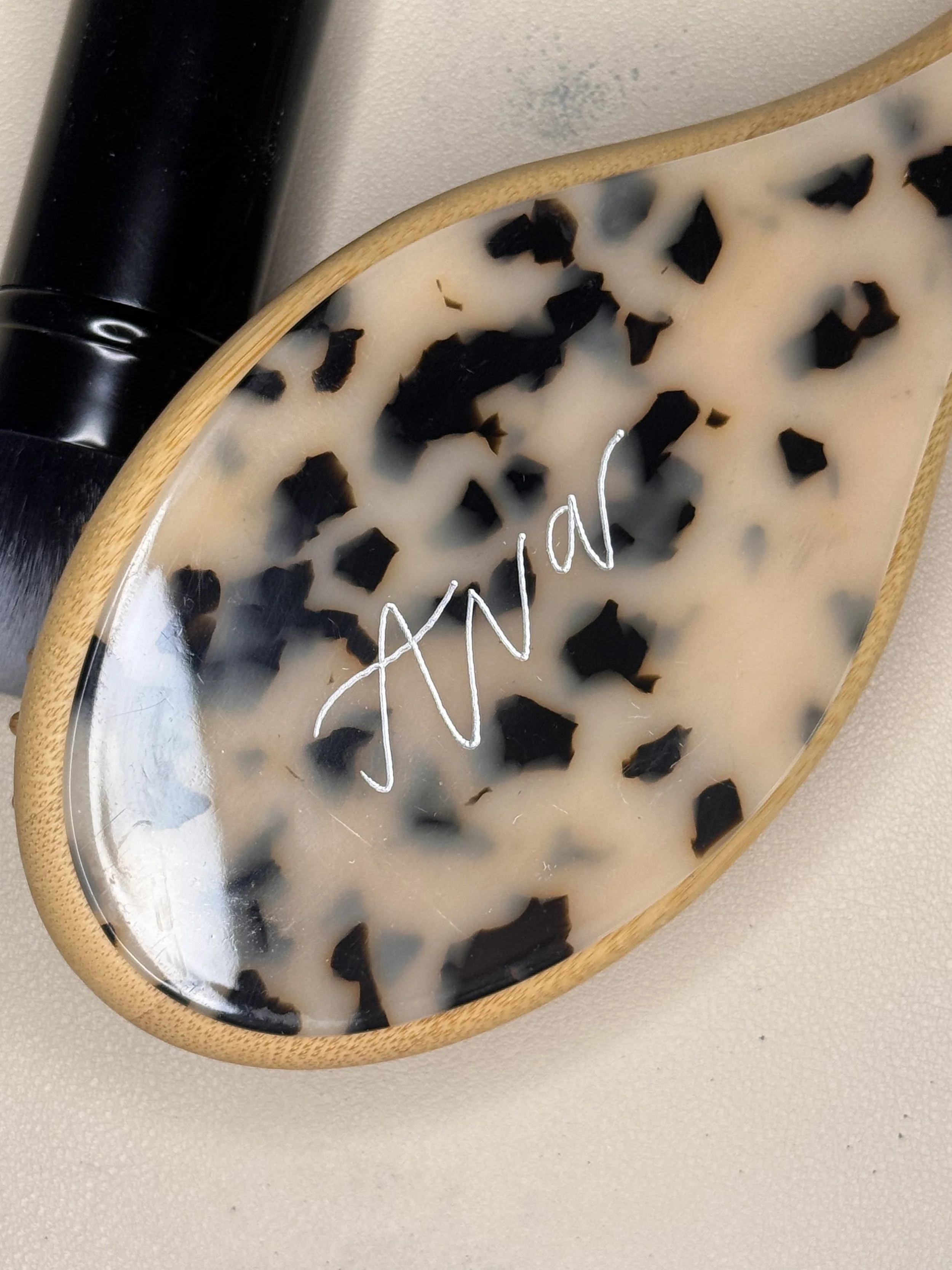 A decorative tray with a leopard print design, a black cylindrical object, and a metallic wire shaped in a zigzag pattern on a neutral surface.