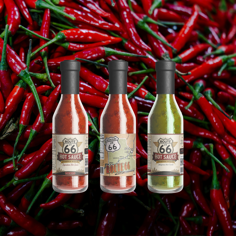 Three bottles of hot sauce against a background of red chili peppers with green stems.