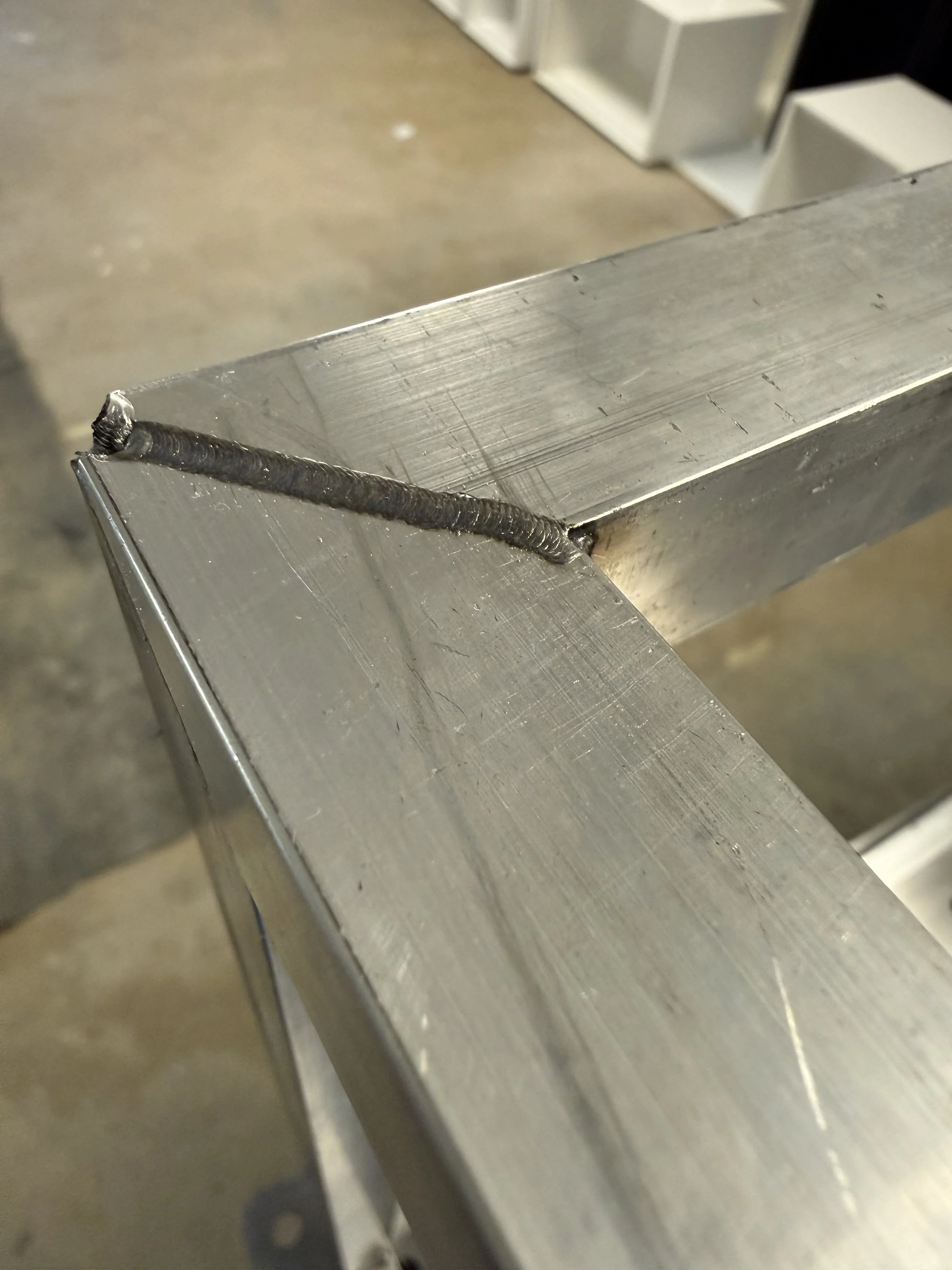 Close-up of a steel piece with a welded joint, showing the weld bead along the edge.