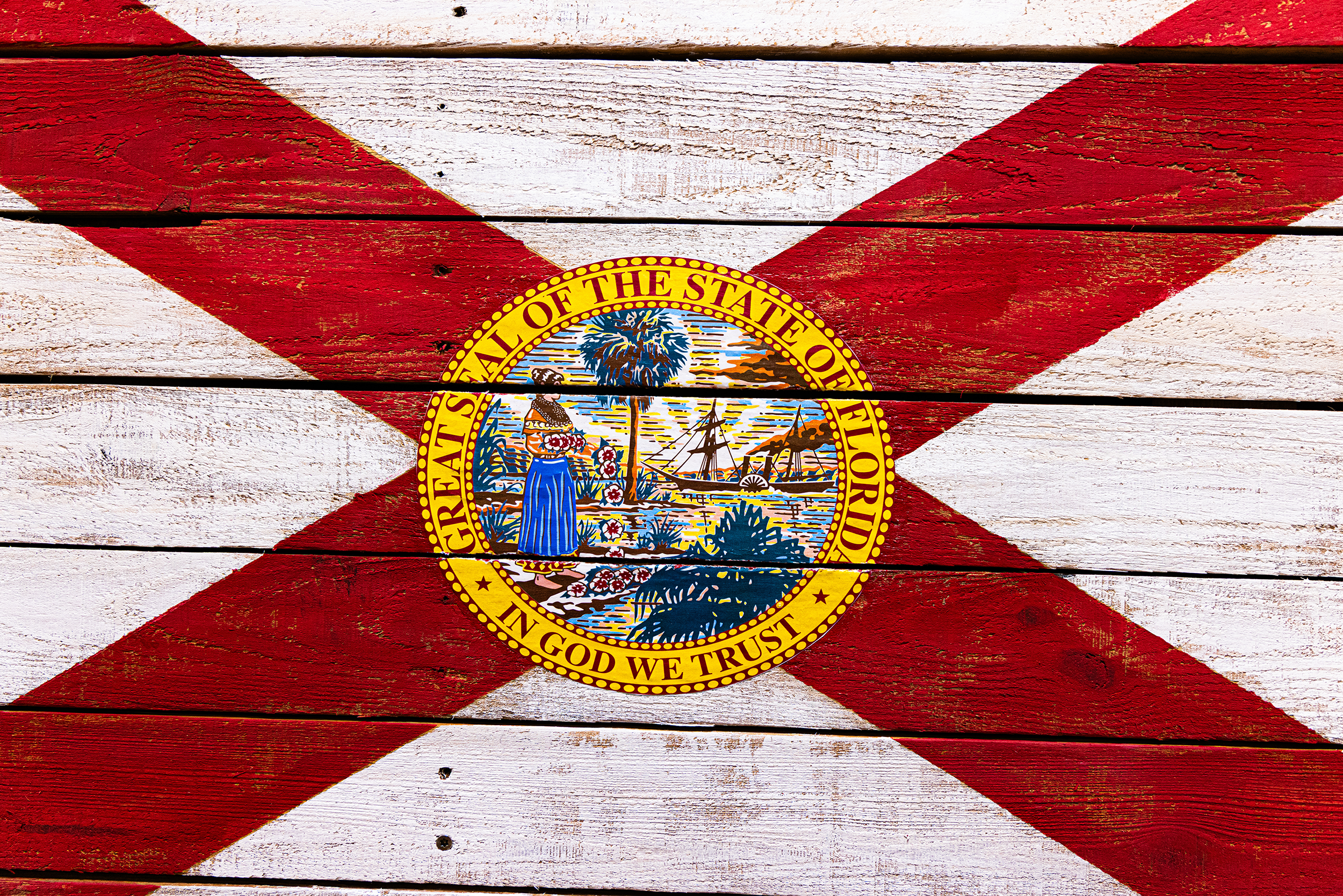 Painted wooden surface with the Oregon state flag, featuring a red diagonal cross and the state seal at the center.