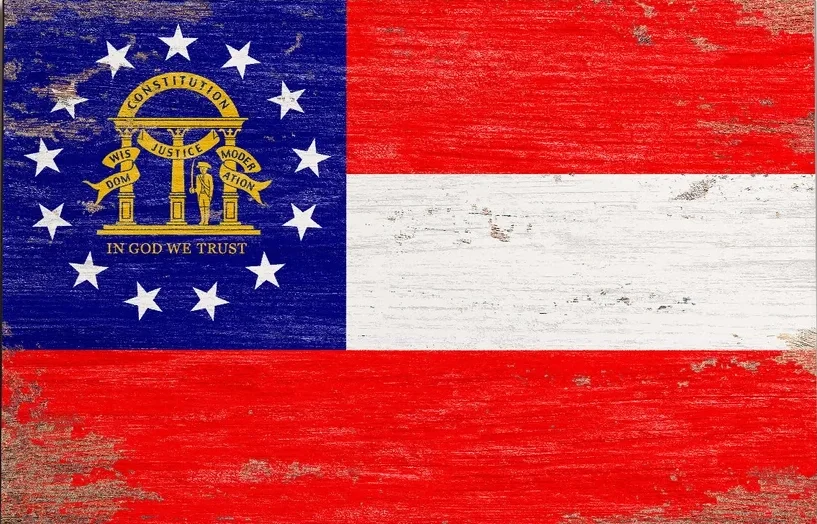 A distressed American flag with the Georgia state flag superimposed in the top left corner, featuring a blue canton with the state seal and 13 stars, and the rest of the flag displaying red and white stripes.