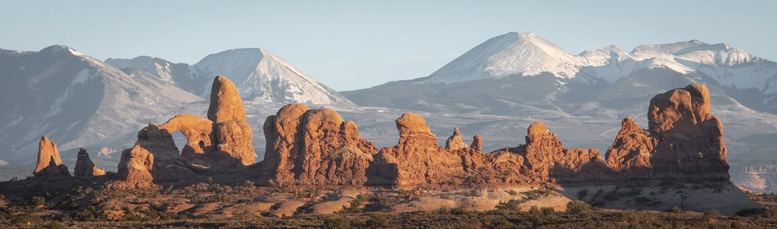 Rock formations in the foreground with snow-capped mountains in the background during daylight.