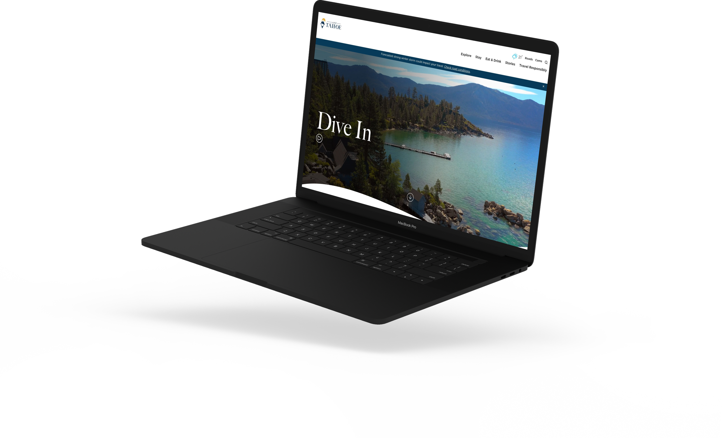 A black MacBook Pro laptop open to a website about Lake Tahoe, showing a scenic view of mountains, trees, and a lake with the phrase "Dive In" on the screen.