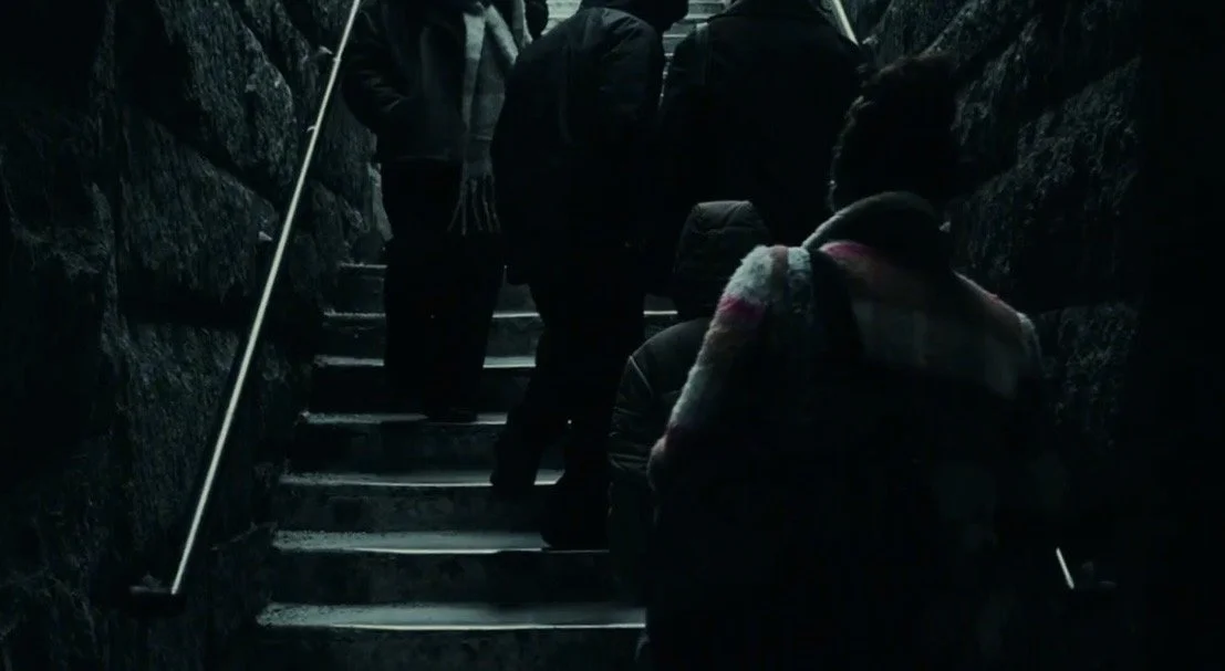 People ascending a dark outdoor stone stairway.
