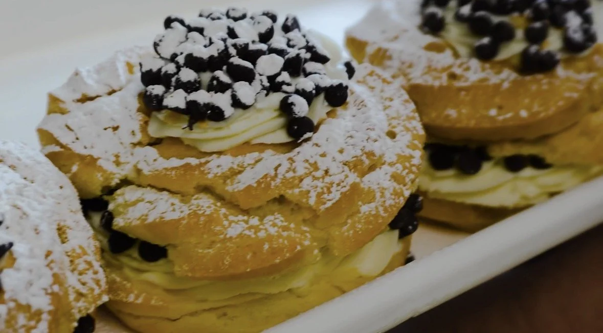 Cream-filled pastries topped with powdered sugar and chocolate chips.