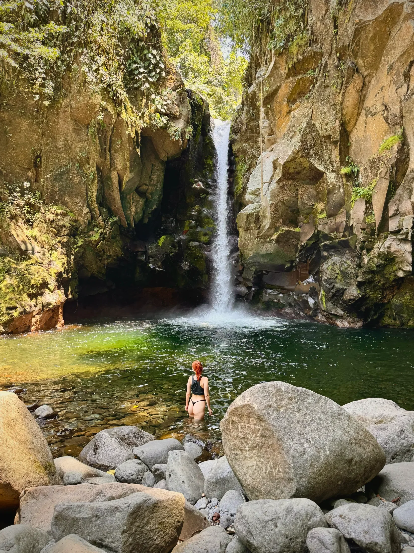 Woman relaxing in a pond with a waterfall in Costa Rica