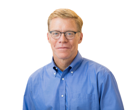 Portrait of a middle-aged man with short blonde hair and glasses, wearing a blue button-up shirt, against a plain white background.