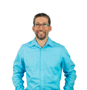 Smiling man in a blue button-up shirt and glasses, posing against a plain white background.